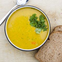 a bowl of soup next to a slice of bread