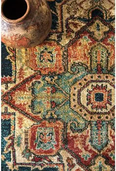 a vase sitting on top of a colorful rug