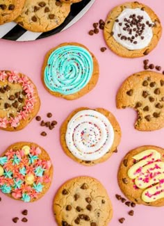 chocolate chip cookies with frosting and sprinkles on a pink surface next to other cookies