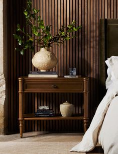 a bed sitting next to a wooden table with a potted plant on top of it