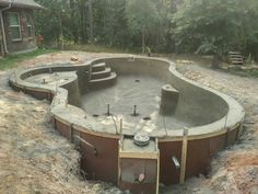 an above ground swimming pool in the middle of a yard with trees and dirt around it