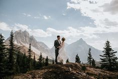 a bride and groom standing on top of a mountain