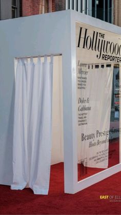 the hollywood reporter booth is set up on red carpeted area with white walls and curtains