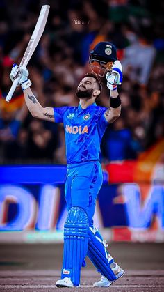 a man with a beard holding a cricket bat and wearing a blue uniform while standing on a field