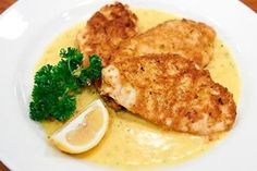 two pieces of fish on a plate with lemon sauce