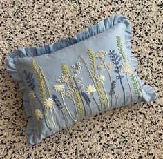 a blue pillow with embroidered flowers on it