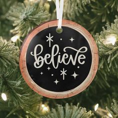 a black ornament hanging from a christmas tree with the words believe on it