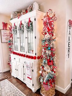 a white china cabinet decorated with red and silver ornaments