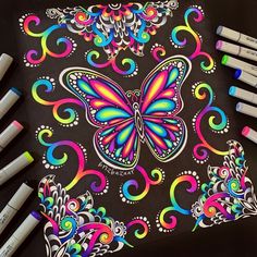 several markers and pens are sitting next to a drawing pad with a butterfly on it