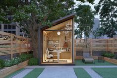 a small garden office is built into the side of a fenced in backyard area