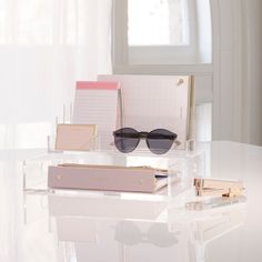 a pair of sunglasses sitting on top of a clear table next to a pink box