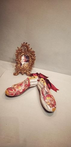 three pairs of shoes sitting on top of a table next to an ornate framed picture