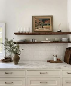 a kitchen with white cabinets and shelves filled with plates, bowls and utensils