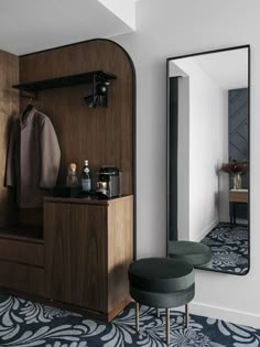 a room with a mirror, stool and coat rack