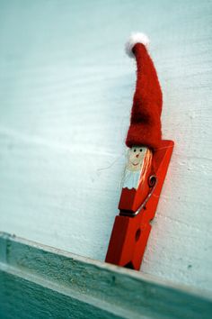 a red piece of wood with a santa clause hat on it's head hanging from the side of a wall