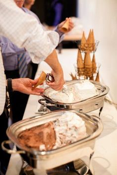 two people are serving themselves ice cream and cake at a buffet table with other desserts