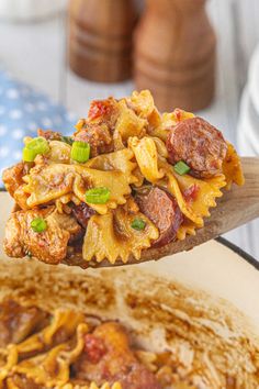 a wooden spoon filled with pasta and meat