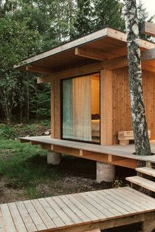 a small wooden cabin in the woods with stairs leading up to it