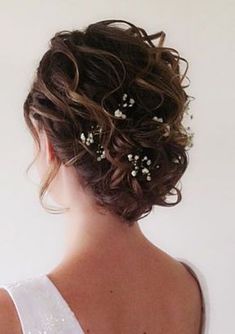 the back of a woman's head with flowers in her hair, wearing a white dress