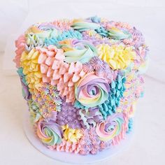 a multicolored cake with icing flowers on top