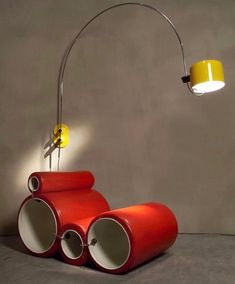 a lamp that is on top of a table next to some red pipes and a yellow light