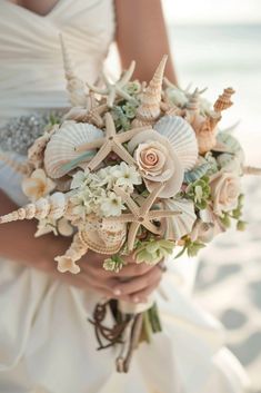 a bride holding a bouquet with seashells and flowers