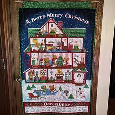 a very merry christmas quilt hanging on a door way with teddy bears in the house