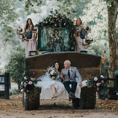 a bride and groom are sitting on the back of a tractor with their bridal party