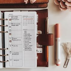 an open planner and pen sitting on top of a desk next to a wallet, notepad