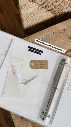 an open book with a pen on top of it next to a wooden table and chair