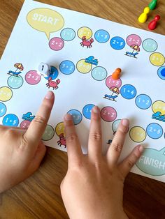 a child's hands on a board game with numbers and push button buttons in front of it