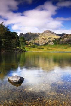 an image of a mountain lake with rocks in the foreground and clouds in the background