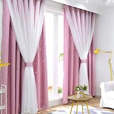 a living room with pink curtains and white furniture