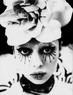 a woman with makeup and flowers on her head is shown in black and white photo