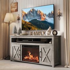 an entertainment center with a fireplace in the middle and mountains on the wall behind it