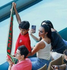 a woman taking a photo with her cell phone while sitting in the stands at a baseball game