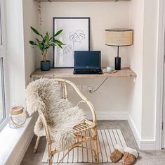 a laptop computer sitting on top of a wooden shelf next to a chair and lamp