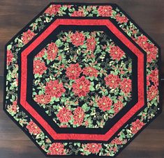 a black and red plate with flowers on it sitting on top of a wooden table