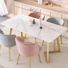 a marble dining table with gold legs and four chairs around it in a living room