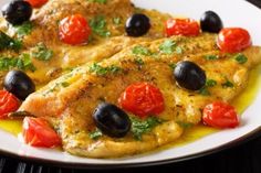 two pieces of chicken with olives and tomatoes on a white plate