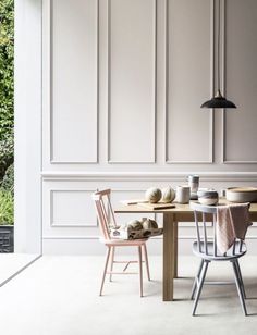 a dining table with two chairs next to an open door that leads into a garden