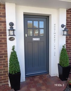 a blue front door with two black planters