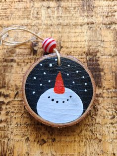 a wooden ornament with a snowman on it's face and a candy cane