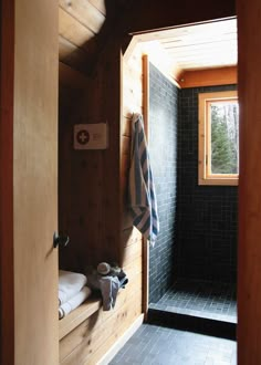 a bathroom with black tile and wooden walls, along with a window on the far wall