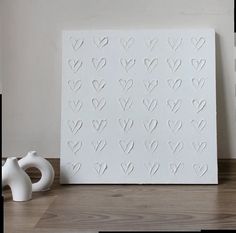 two white vases sitting on top of a table next to a paper cutout