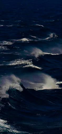 two surfers are riding the waves in the dark blue ocean, one is on his surfboard