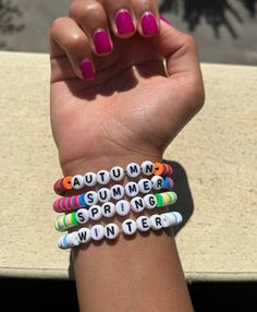 a woman's arm with four bracelets on it and the word autumn spelled in small letters