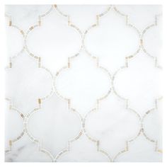 a white and gold tile wall with an intricate design on the bottom half of it