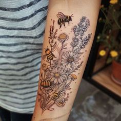 a woman's arm with flowers and bees on it