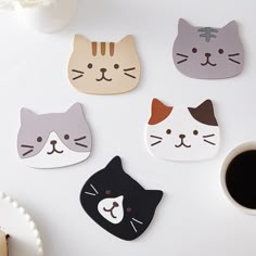 four cat coasters sitting on top of a white table next to a cup of coffee